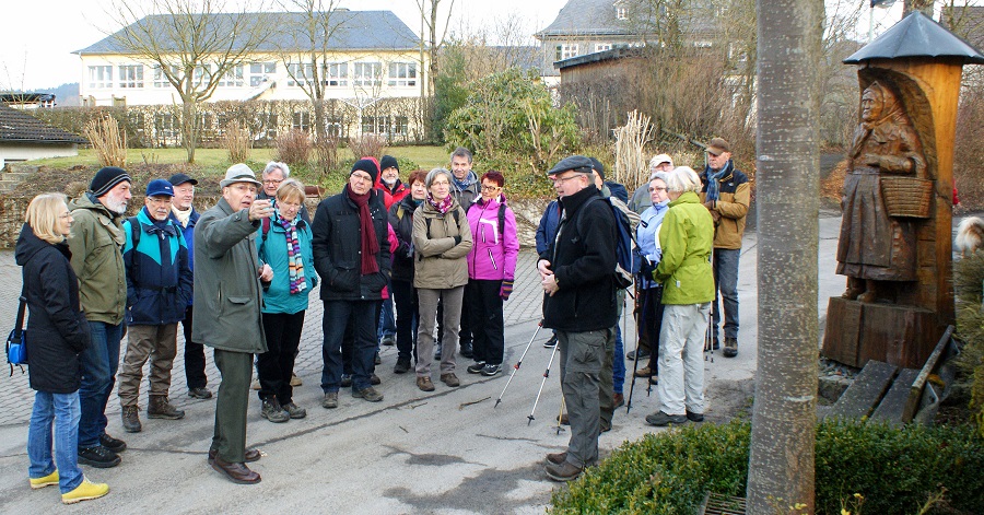Das Hellefelder Urgestein Paul Grothe empfängt die SGV-Wandergruppe an der hölzernen Butterbettchen-Statue in Hellefeld. (Foto: Klaus Peters)