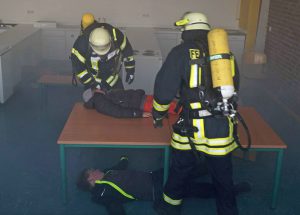 Feuerwehrleute unter Atemschutz in einem der künstlich verrauchten Klassenzimmer. (Foto.:Feuerwehr)