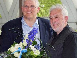 Bürgermeister Hans-Josef Vogel überreichte Werner Frin (r.) in der Ratssitzung einen Blumenstrauß. (Foto: Elena Segalen)